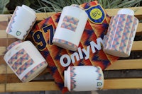 a group of mugs with a soccer shirt on them sit on a bench