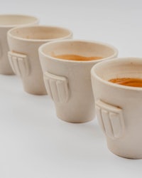 four coffee cups lined up on a white surface