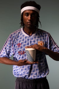 a man with dreadlocks holding a cup